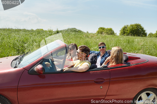 Image of happy friends driving in cabriolet car and talking