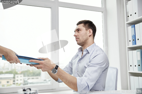 Image of businessman taking papers from secretary in office