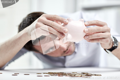 Image of businessman with piggy bank and coins at office