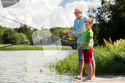 Image of grandfather and grandson fishing on river berth