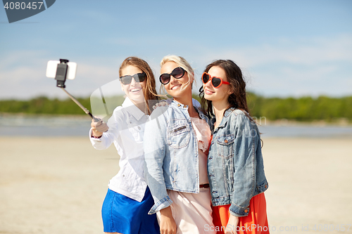 Image of group of smiling women taking selfie on beach