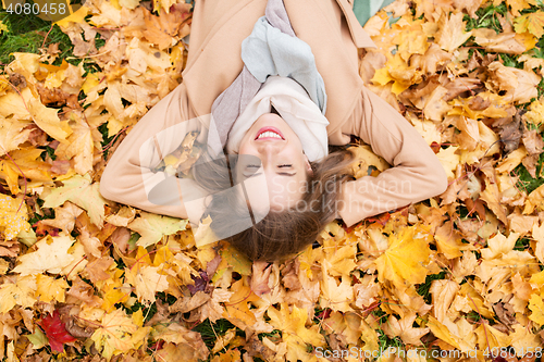 Image of beautiful happy woman lying on autumn leaves