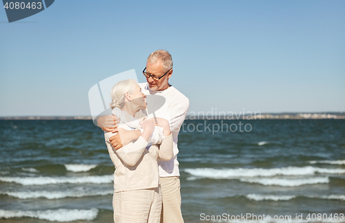 Image of happy senior couple hugging on summer beach