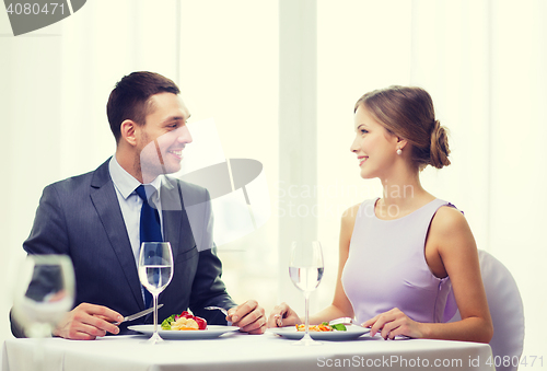 Image of smiling couple eating main course at restaurant