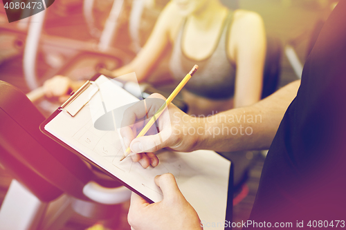 Image of close up of trainer hands with clipboard in gym