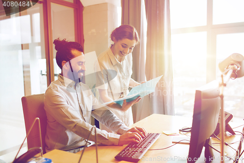 Image of happy creative team with computer in office