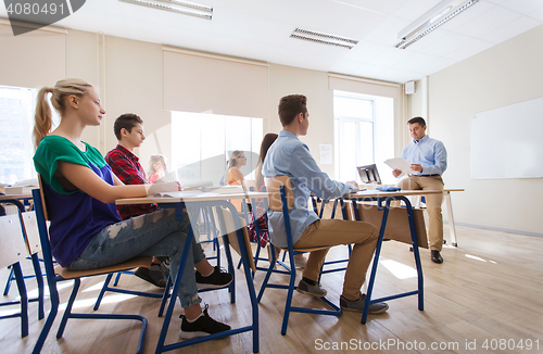 Image of group of students and teacher with papers or tests