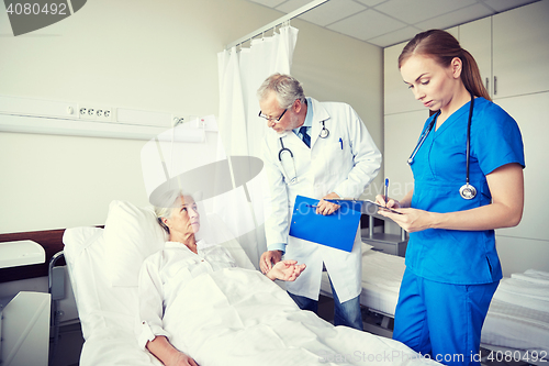 Image of doctor and nurse visiting senior woman at hospital