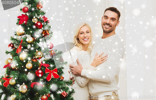 Image of happy couple hugging near christmas tree at home