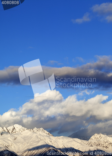 Image of Snow winter mountains in clouds at sun evening