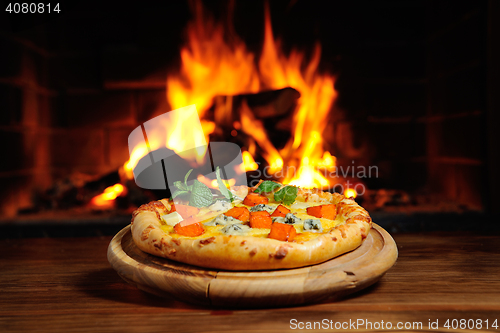 Image of pizza with a pumpkin on  background of fire. Dish  Halloween