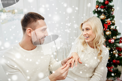 Image of man giving engagement ring to woman for christmas