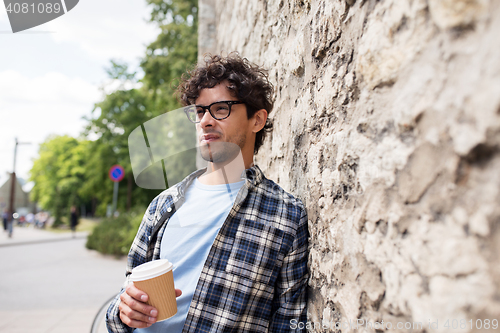 Image of man in eyeglasses drinking coffee over street wall