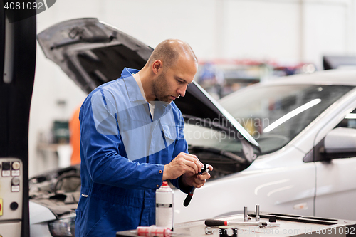 Image of mechanic man with wrench repairing car at workshop