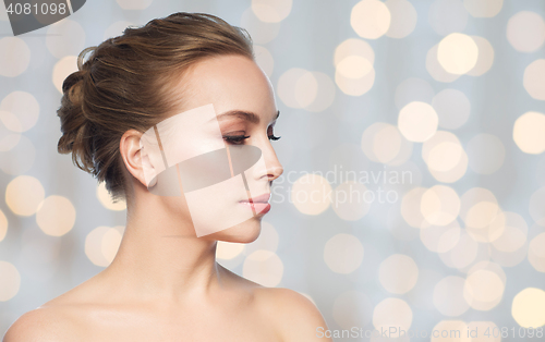 Image of beautiful young woman face over holidays lights