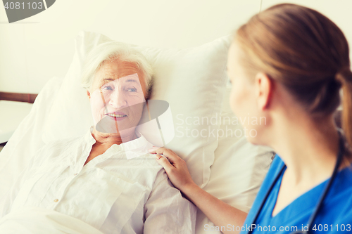 Image of doctor or nurse visiting senior woman at hospital