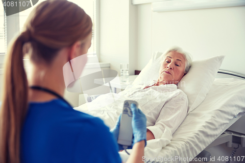 Image of doctor or nurse visiting senior woman at hospital