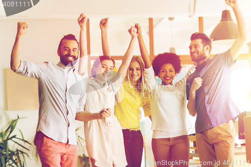 Image of happy creative team celebrating victory in office