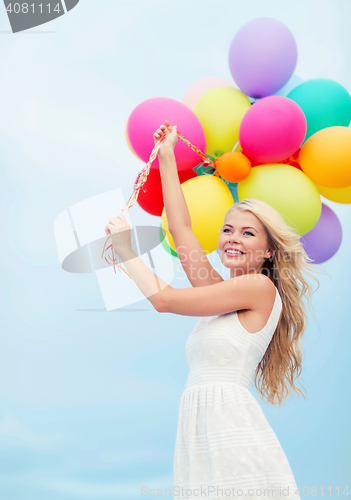 Image of smiling woman with colorful balloons outside