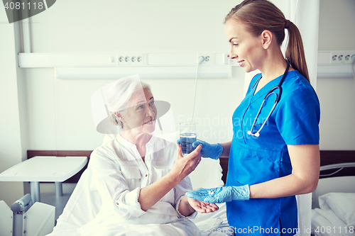 Image of nurse giving medicine to senior woman at hospital