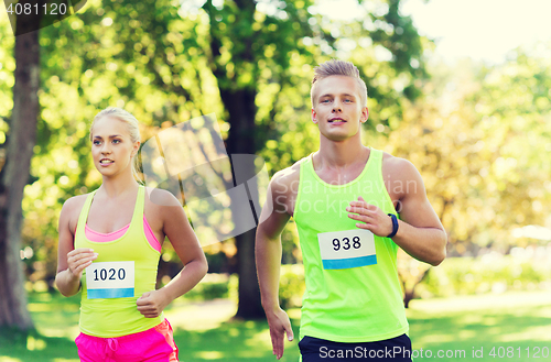 Image of happy sportsmen couple racing wit badge numbers