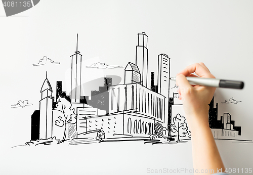 Image of close up of hand drawing city on white board