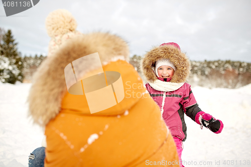 Image of happy family in winter clothes playing outdoors