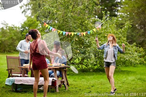 Image of happy friends playing badminton at summer garden