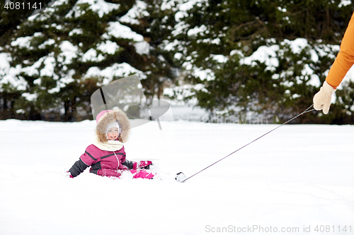 Image of happy little kid riding on sled outdoors in winter