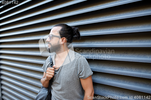Image of man with backpack standing at city street wall