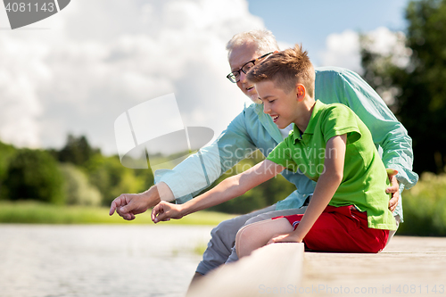 Image of grandfather and grandson sitting on river berth