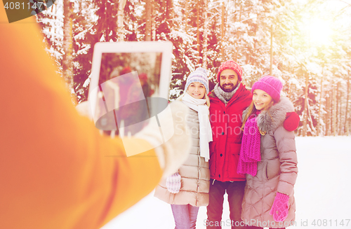 Image of smiling friends with tablet pc in winter forest