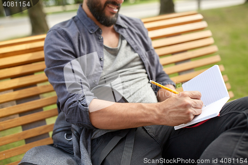 Image of close up of man writing to notebook on city street