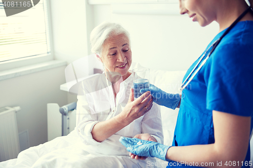 Image of nurse giving medicine to senior woman at hospital