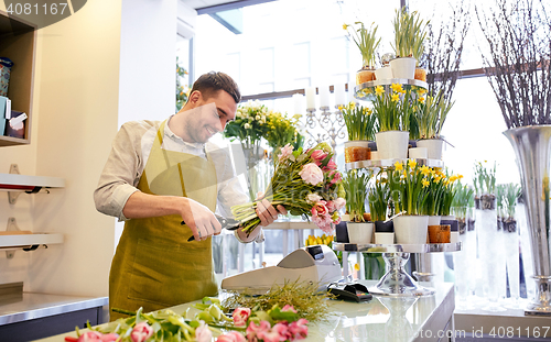 Image of smiling florist man making bunch at flower shop