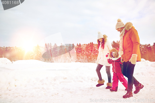 Image of happy family in winter clothes walking outdoors