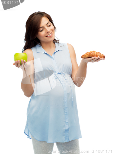 Image of happy pregnant woman with apple and croissant