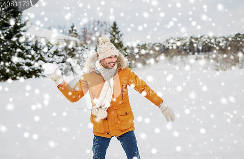 Image of happy young man playing snowballs in winter