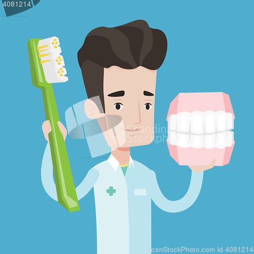 Image of Dentist with dental jaw model and toothbrush.