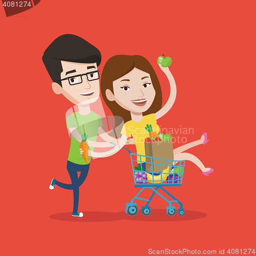 Image of Couple of friends riding by shopping trolley.