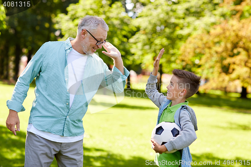 Image of old man and boy with soccer ball making high five
