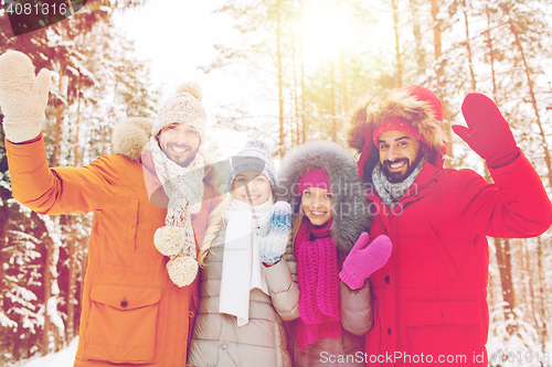 Image of group of friends waving hands in winter forest