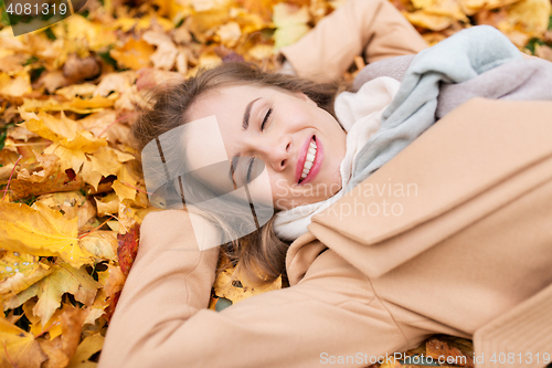 Image of beautiful happy woman lying on autumn leaves