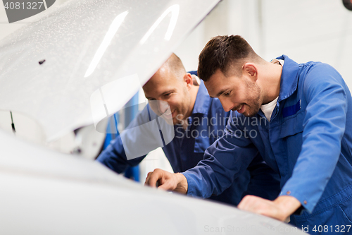 Image of mechanic men with wrench repairing car at workshop