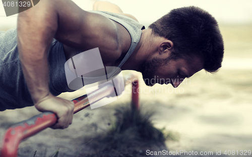 Image of young man exercising on horizontal bar outdoors