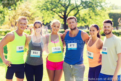 Image of happy friends or couple with racing badge numbers