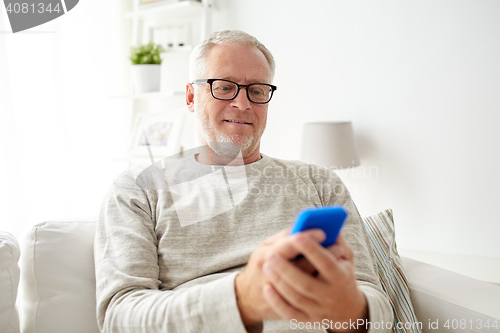 Image of happy senior man texting on smartphone at home