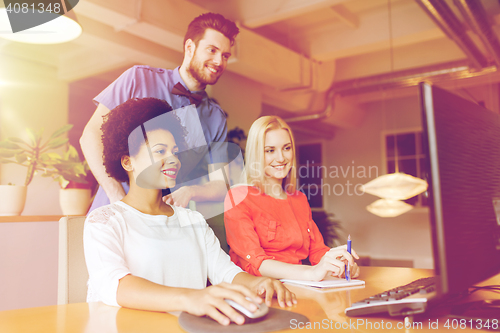 Image of happy creative team with computer in office