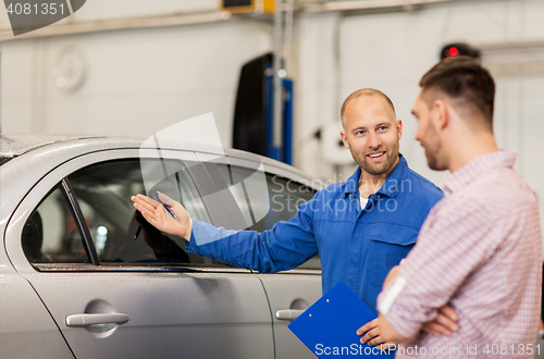 Image of auto mechanic with clipboard and man at car shop