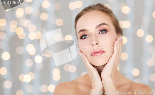Image of beautiful woman touching her face over lights